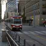 A Red Line CTrain travelling along 7 Avenue into City Hall station between downtown office towers