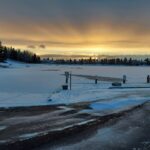 Snow-covered Lake Midnapore at sunset in early winter, with a roped-off beach area in the foreground