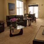 Tidy living room with leather sofas, a glass coffee table and a dining nook by the patio door in a Calgary townhome