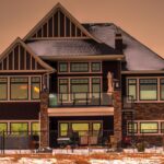 Two-storey craftsman-style detached house with stone accents and large windows at sunset in Calgary
